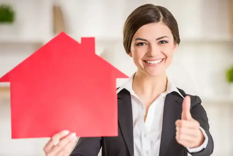 Propriétaire satisfaite tenant une maquette de maison après l'estimation de son bien